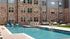 Inviting apartment complex featuring a luxurious swimming pool with comfortable lounge chairs, surrounded by elegant stone architecture.