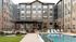 Stunning apartment complex featuring modern architecture, inviting pool, and elegant outdoor lounge area with seating.