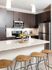 Modern kitchen with sleek dark cabinets, stainless steel appliances, and a chic breakfast bar accented by warm wooden stools.