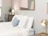 Bright and cozy bedroom with modern decor, featuring a comfortable bed, stylish lamp, and abstract wall art.