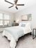 Bright and welcoming bedroom featuring a cozy bed, modern artwork, and a stylish ceiling fan.