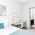 Charming bedroom with a modern desk setup, cozy bed, and en-suite bathroom, perfect for stylish urban living.
