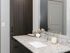 Elegant bathroom vanity with sleek granite countertop, chic dark wood cabinetry, and stylish gold-accented fixtures.