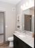 Modern bathroom with elegant granite countertop, sleek sink, and ambient lighting, leading to a spacious walk-in closet.