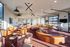 Modern and inviting communal lounge area with elegant brown leather chairs and unique lighting fixtures, perfect for social gatherings and relaxation.