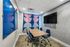 Modern meeting room with contemporary decor, featuring a wooden conference table, stylish blue chairs, and vibrant geometric curtains.