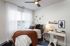 Cozy and stylish bedroom with modern decor, featuring a comfortable bed with plush cushions, chic wall art, and a functional workspace illuminated by natural light through sheer curtains.