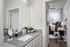 Modern apartment highlighting a sleek bathroom vanity with granite countertop, leading to a cozy, well-lit bedroom with stylish decor.