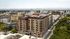 Modern urban apartment complex with panoramic city views, featuring contemporary architecture and lush greenery nearby.