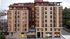Modern urban apartment building with sleek architecture, large windows, and rooftop garden.