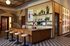 Chic and modern co-working space featuring wooden shelves with plants and books, a large wooden desk with beige stools, and artistic wall decor for an inspiring work environment.