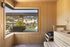 Inviting sauna room with warm wood paneling and a picturesque window view of lush greenery and residential landscape.