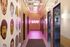 Chic apartment hallway with vibrant wall art and modern elevators, enhanced by ambient pink lighting.