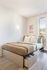 Cozy bedroom featuring a stylish bed with built-in storage, soft lighting, and a scenic window view.