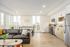 Modern open-plan living room with sleek kitchen, stylish furniture, and abundant natural light.