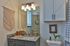 Charming bathroom featuring a granite countertop, elegant lighting, and stylish woven wall art, exuding a cozy, modern vibe.