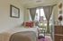 Inviting bedroom with cozy bed, elegant decor, and large window offering natural light and serene views.