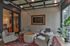 Chic enclosed seating area with cozy armchairs around a modern coffee table on a vibrant red rug, accented by large windows and elegant decor.