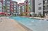 Modern apartment complex with vibrant colors, featuring a luxurious pool area with lounge chairs and poolside seating.