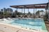Luxurious rooftop pool with elegant lounge area, featuring sleek sun loungers and a modern pergola, offering stunning city views.