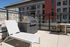 Modern rooftop patio with a sleek barbecue grill, stylish lounge chair, and comfortable dining set, ideal for outdoor entertainment.