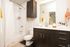 Modern bathroom featuring a sleek vanity, elegant sink, and stylish bathtub with a tiled backsplash.