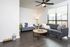 Bright and inviting living room with modern gray sofas, sleek wooden flooring, and a chic coffee table, illuminated by ample natural light from large windows.