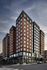 Modern high-rise apartment building with sleek design, large windows, and a vibrant urban setting.
