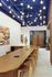 Contemporary conference room with sleek wooden table, modern art, vibrant ceiling lights, and elegant double doors.