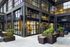 Modern urban apartment exterior with large windows and stylish outdoor seating area surrounded by lush greenery.