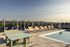 Chic rooftop pool area featuring elegant lounge chairs and shaded cabanas with stunning city and mountain views.