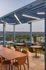 Modern rooftop terrace with stylish seating, vibrant cityscape views, and sleek overhead lighting.