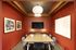 Contemporary meeting room with vibrant red walls, elegant artwork, and a modern wooden table set for six.