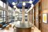 Chic and modern lounge area with a long wooden table, stylish lighting, and floor-to-ceiling windows for ample natural light.