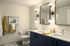 Elegant bathroom with double sinks, sleek navy cabinetry, and modern round mirrors under chic globe lighting.