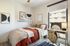 Chic and cozy bedroom with modern decor, featuring a plush bed, stylish art, and a bright workspace by the window.