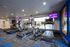 Modern fitness center with treadmills and exercise bike, featuring vibrant lighting and wall displays.