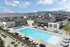 Modern apartment complex with scenic mountain views, featuring luxurious swimming pool, sun loungers, and stylish clubhouse.