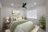 Inviting bedroom with stylish decor, featuring a plush bed with green accents, elegant lighting, and vibrant indoor plant.