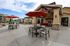 Charming outdoor patio space featuring stylish red umbrellas, contemporary seating, and a cozy fireplace in a serene apartment complex setting.