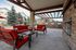 Inviting outdoor patio with red cushioned seating, modern grill stations, and charming wooden pergola, perfect for entertaining.