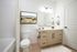 Elegant bathroom featuring modern vanity with sleek faucets, stylish artwork, and luxurious fixtures.