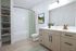 Modern bathroom with elegant vanity, stylish open shelving, and inviting tub featuring a chic green curtain.