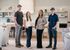 Bright and inviting modern living space with a team of four smiling people, featuring elegant shelving, cozy furniture, and a welcoming atmosphere.