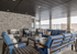 Inviting outdoor lounge area featuring stylish blue cushioned seating, a modern stone fireplace, and a sleek dark ceiling design.