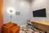 Modern study room with a sleek wall-mounted TV, cozy orange armchair, and a stylish workspace desk with ergonomic chair.
