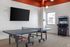 Contemporary recreational room featuring a sleek table tennis setup, modern arcade machine, and wall-mounted flat-screen TV, perfect for entertainment and leisure.