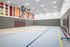 Modern indoor sports court with a vibrant, colorful wall design, featuring a basketball hoop and clean, spacious flooring.