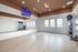 Bright and modern fitness room with a large mirror, sleek wooden flooring, and a fully equipped workout station.