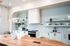 Sleek modern kitchen featuring elegant pendant lighting, minimalist cabinets, and open shelving with tasteful decor.
